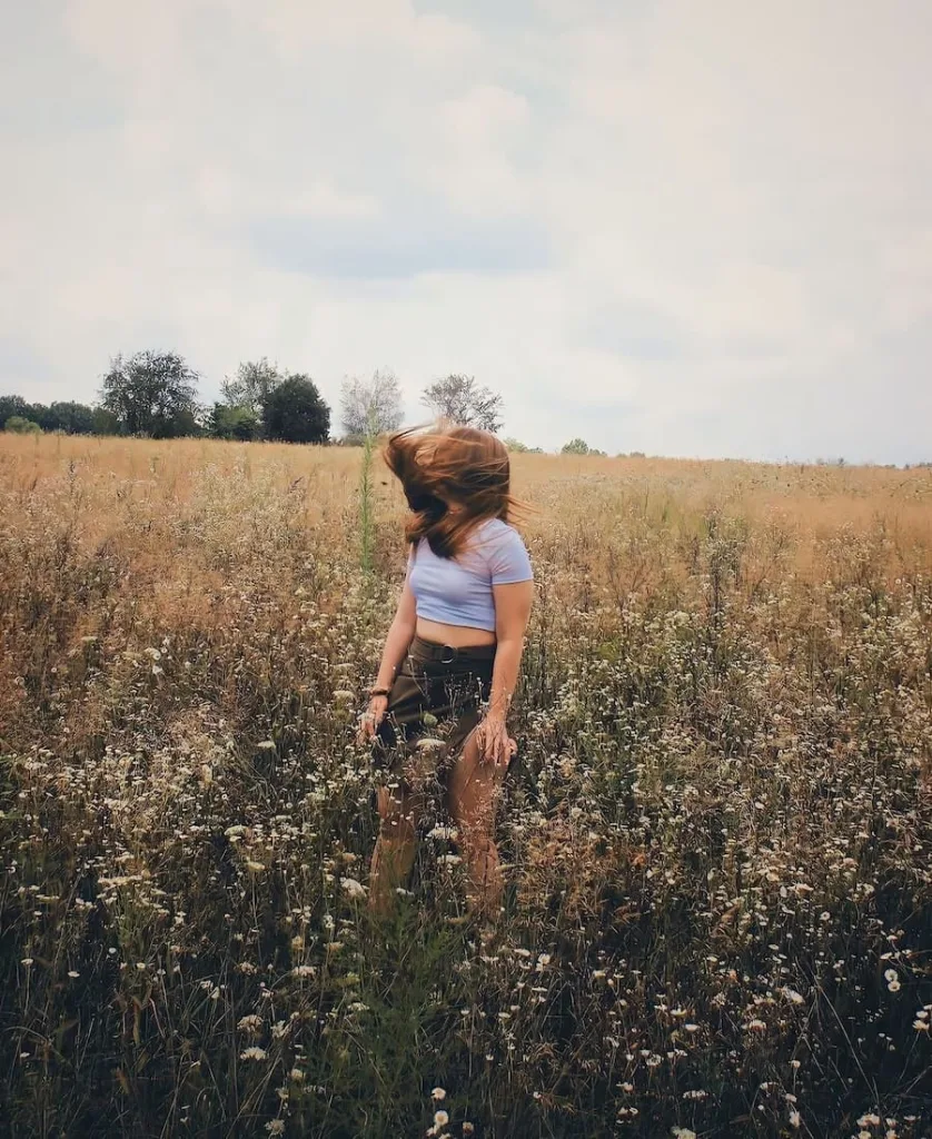 woman in field with flowers feeling vibrations